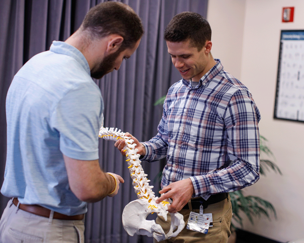 Nurse showing patient model spine